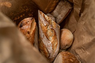 Différents types de pain français, notamment des baguettes, du pain au levain et des pains de campagne, présentés pour comparaison.