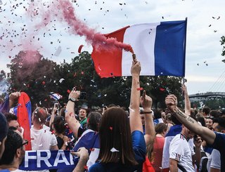 Des habitants d’un village en Occitanie célèbrent le Tour de France, décorations, drapeaux et foules rassemblées le long de la route.
