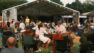 Families and friends gathered around long outdoor tables enjoying food and celebrating at village fêtes in France in Occitanie. Families and friends gathered around long outdoor tables enjoying food and celebrating at village fêtes in France in Occitanie.